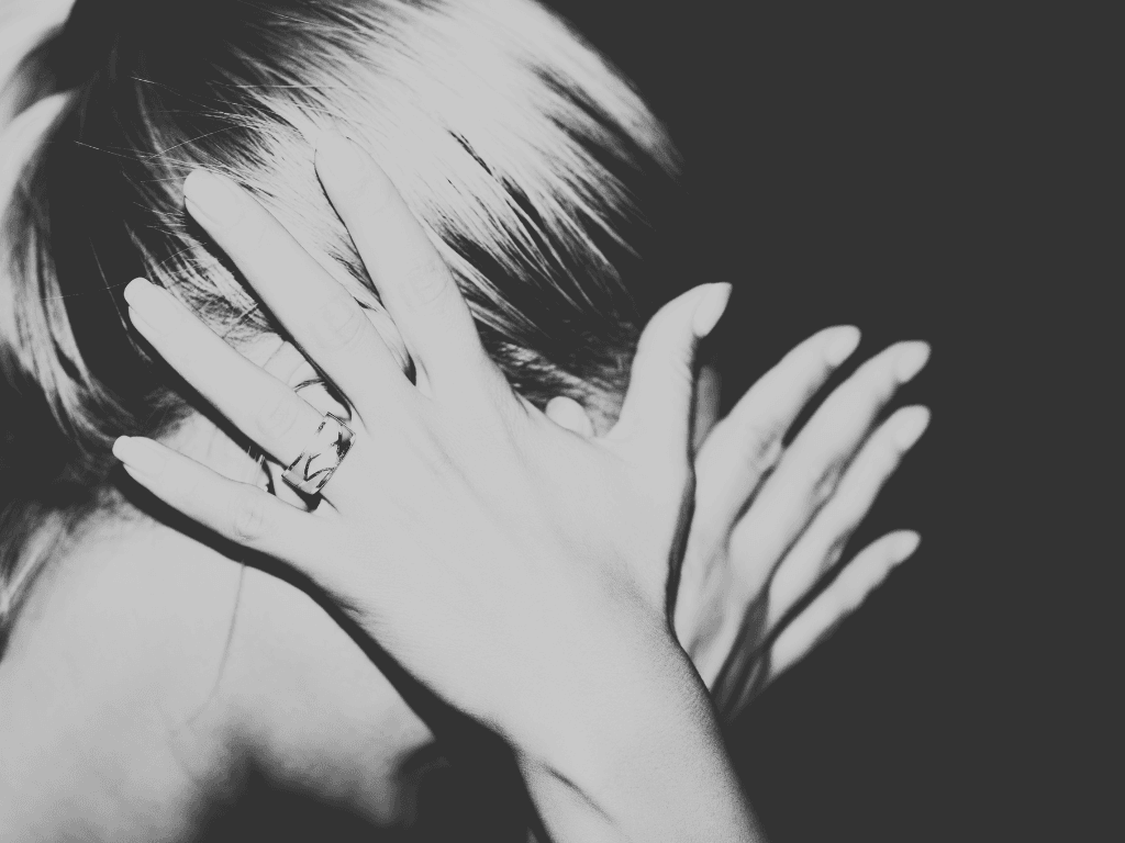 A woman covering her face with both hands, photographed in black and white