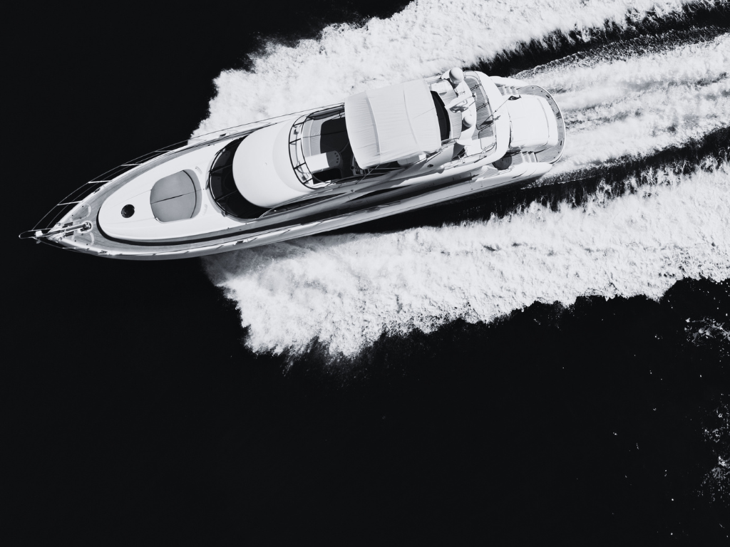 Aerial view of a luxury yacht cutting through dark water, representing premium brand experience